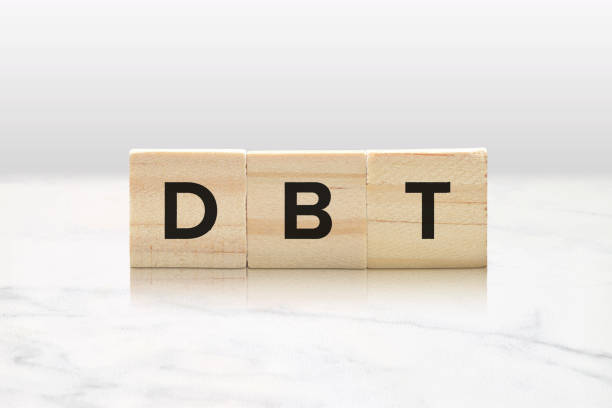 Three wooden blocks spelling DBT on a bright surface